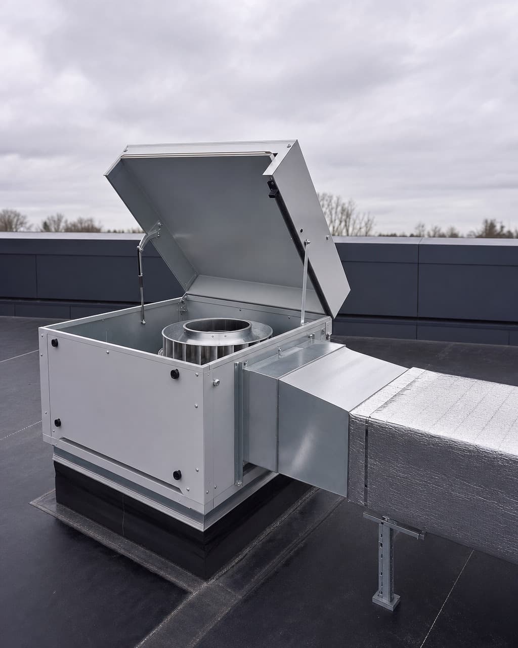 Un caisson de ventilation en toiture terrasse, sa turbine visible par le capot ouvert